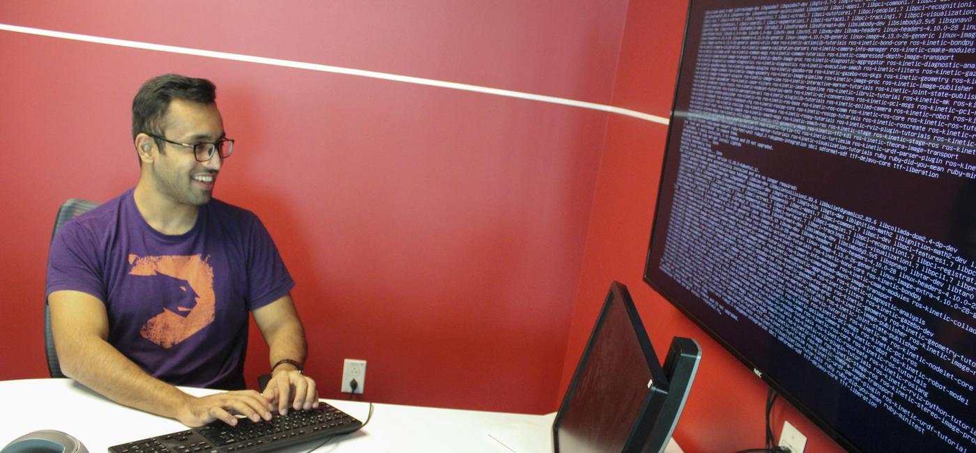 man at a table typing on a keyboard and looking at a separate computer screen